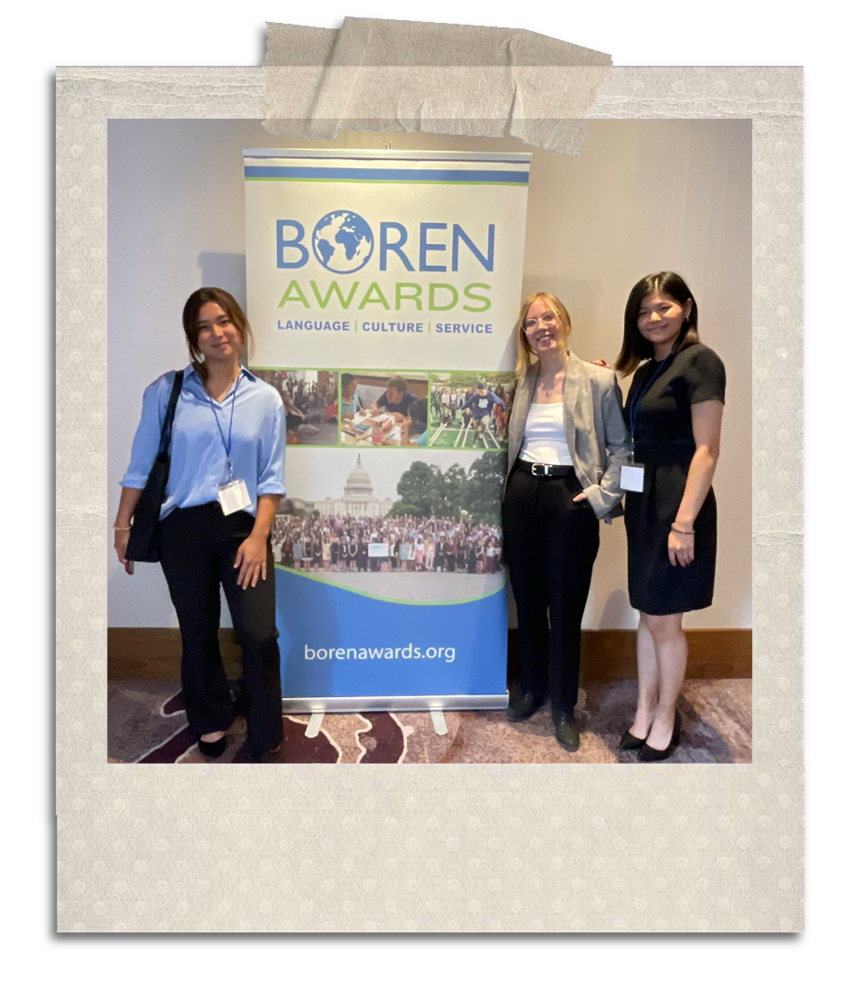 An image of the author in professional dress standing with two people in front of a banner that says Boren Award.